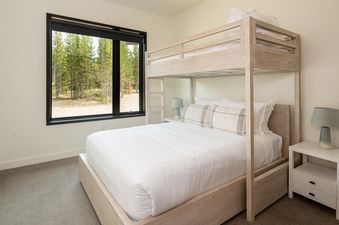 The bedroom at Moonlight Basin 221 Lakelodge features a bunk bed, a large window, and a bedside table.