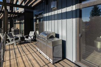 A modern outdoor living space with a large stainless steel BBQ grill and a wooden deck.