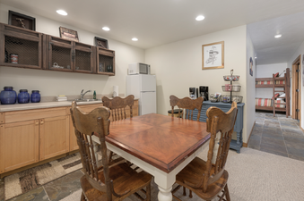 The dining table with four wooden chairs is set in the kitchen area of 2665 Golden Eagle Drive, featuring a sink, microwave, refrigerator, and decorative elements.