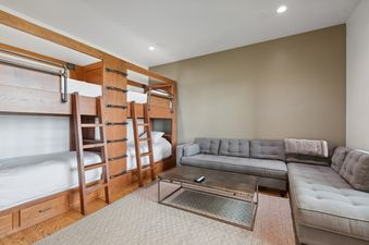 A bunk bed room at the Swan Lake House with a large gray sectional sofa, a rustic coffee table, and patterned rug.