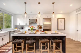 A modern kitchen with white cabinets and a large island with bar stools.
