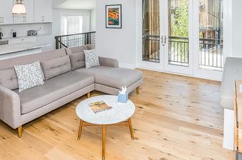 The living room of Boulders Way 126 features a sectional sofa with pillows, a marble top coffee table, a magazine on the coffee table, and hardwood flooring.