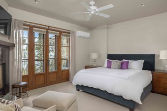 A spacious bedroom with a king-size bed, a large window, and a fireplace.