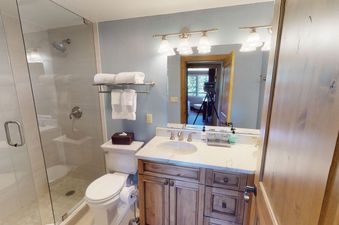 A bathroom with a shower, a toilet, a sink, and a vanity.