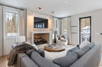 A cozy living room in Lone Star Lodge Mountain Village with a large grey sectional sofa facing a stone fireplace with a mounted television above it.
