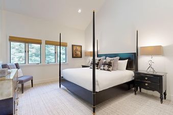 Elegant bedroom at Windriver 2 featuring a black four-poster bed, stylish lamps, and natural light.