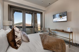 A bright and airy bedroom at Abode at Juniper Ridge is furnished with a TV and balcony access.