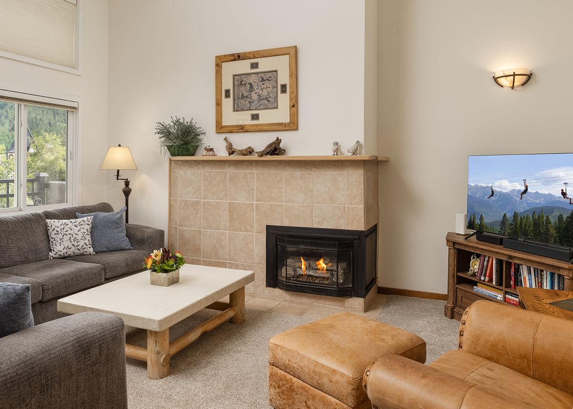 A cozy living room at Vantage Point 504 with a fireplace, television, and mountain views from the window.