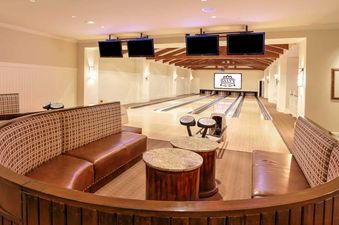 The bowling alley at Montage Resort View Junior Suites features comfortable seating areas, multiple lanes, and large screens displaying scores, all under warm lighting.