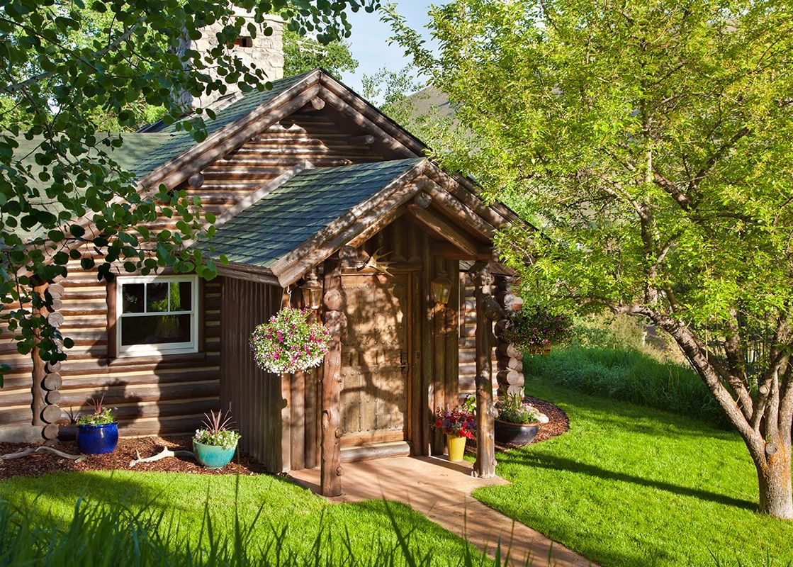 Exterior entrance of The Cabin in Jackson Hole with lush green grass and trees on a sunny day.