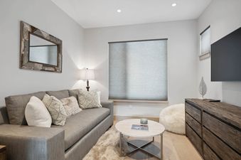 A cozy lounge area in One Riverfront Townhome 05 with a grey sofa, coffee table, and rustic-framed mirror, providing a comfortable and stylish retreat.