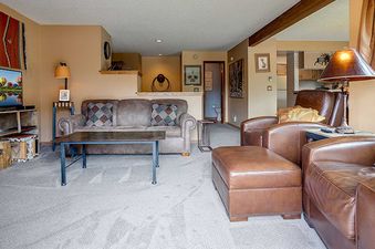 A cozy living room at Ranch at Steamboat RA501 with a brown sofa, armchairs, and a decorative lamp.