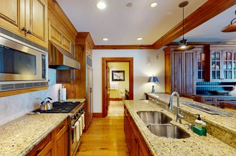 A kitchen area with stainless steel appliances, granite countertops, and wooden cabinets.