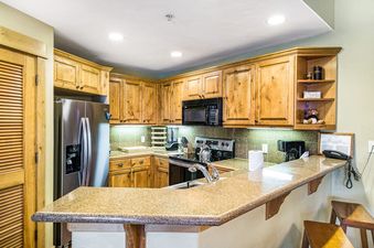A modern kitchen with wooden cabinets, granite countertops, and stainless steel appliances at EagleRidge Lodge 306.