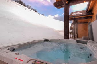 The Retreat at Black Rock Ridge offers a luxurious outdoor hot tub, perfect for relaxing after a day in the snowy mountains.