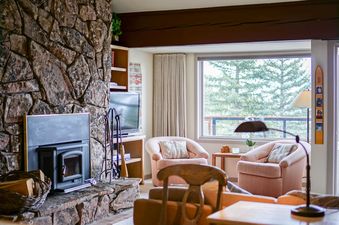 Cozy living room at Snowridge 2 featuring a stone fireplace and large window.