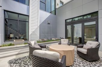 A private patio at Parkite 37 features modern furniture, a leopard print rug, and contemporary architectural elements, including large windows and sleek paneling.