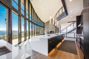 The Deer Crest Estate showcases an expansive interior with floor-to-ceiling windows offering panoramic mountain and lake views.