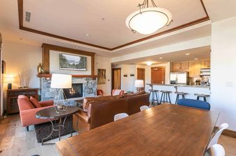 A living room with a fireplace and a dining table in the background