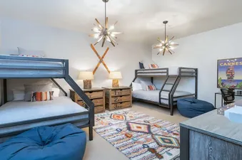 A bedroom with two bunk beds, a desk, and a large window.