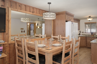 The dining area in Beaver Village 1612 features a large wooden dining table with eight chairs, set with plates and glasses.