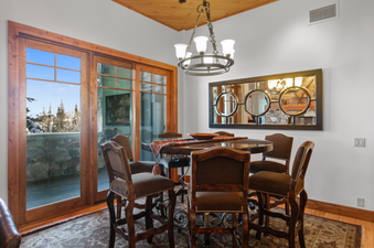The dining area of Grand Lodge Three Bedroom Deluxe 206 is equipped with a table, chairs, and a chandelier.