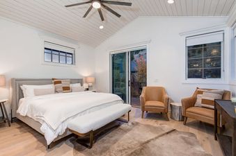 Bright master bedroom at Palomino Ridge with a king bed, leather armchairs, and balcony access.