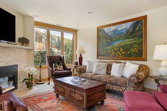Cozy living room at 411 Beaver Creek Lodge with patterned sofa, fireplace, and scenic window views.