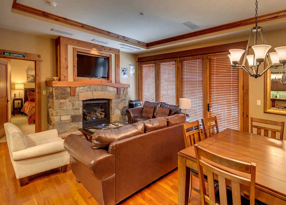 A living room with a fireplace, a leather sofa, a TV, and a dining table.