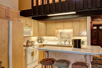 A modern kitchen with wooden cabinets, stainless steel appliances, and a white countertop.