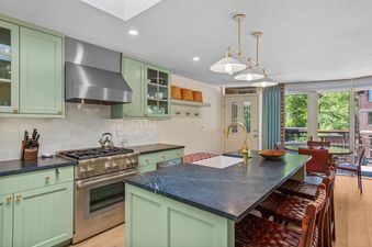 A modern kitchen with green cabinets, stainless steel appliances, and a large island with seating.