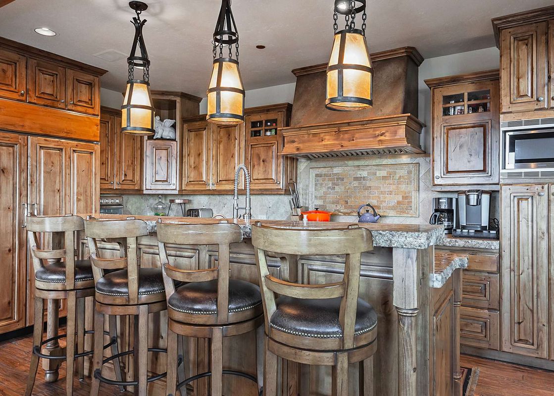 The spacious kitchen at the Retreat at Empire Pass features a large island with bar seating and custom wooden cabinetry.