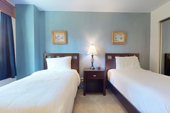 Bedroom at Enzian 116 with two beds and a nightstand.