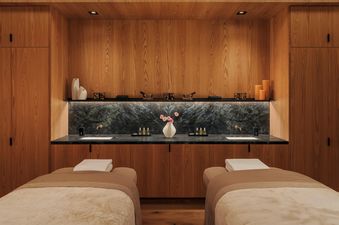 Luxurious double spa treatment room with wood paneling and marble vanity.