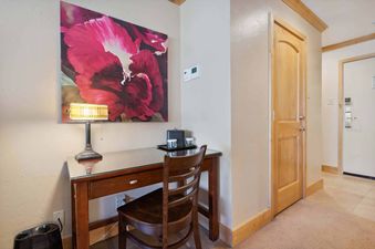 A wooden desk and chair sit beneath an art piece in Lodge Tower 782.