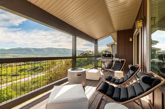 Covered balcony of Deer Valley East Basecamp with loungers, fire bowl, BBQ grill, and stunning mountain views.