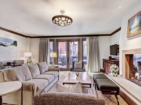 Cozy living area in the Arrabelle King Suite with a large stone fireplace, plush seating, and balcony access.