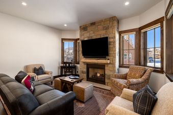 Cozy living room with a stone fireplace and a television at The Bear and Moose Lodge.