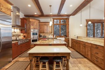 The kitchen at Last Nickel Lodge features rustic wooden cabinetry, modern stainless steel appliances, and a large central island with granite countertops and seating.