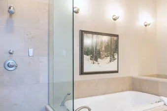 A spacious bathroom features a tiled shower stall with a handheld shower head and a separate white bathtub with jetted features.