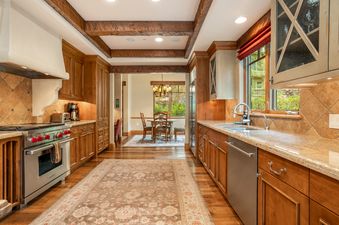 Fully equipped kitchen with rustic wooden cabinets, stainless steel appliances, and ceiling beams at Gore Place.