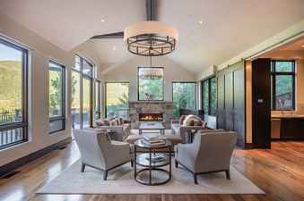 A luxurious and spacious living room with a fireplace, comfortable seating, and large windows offering mountain views.