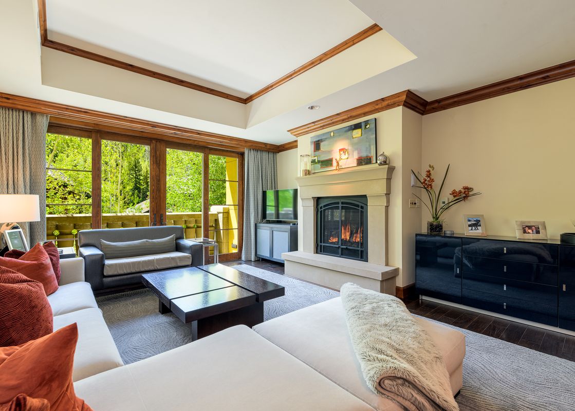 A spacious living room with a fireplace, large windows, and two couches.