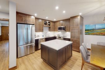 Modern kitchen with stainless steel appliances, dark wood cabinets, and a breakfast bar.