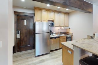 The kitchen in Manor Vail 163 has stainless steel appliances, a granite countertop, and a breakfast bar.