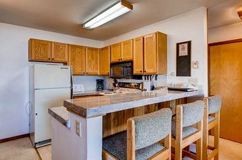 A functional kitchen at Buttes 2 Peak 517, featuring a full-size refrigerator, microwave, and a breakfast bar with seating for two.