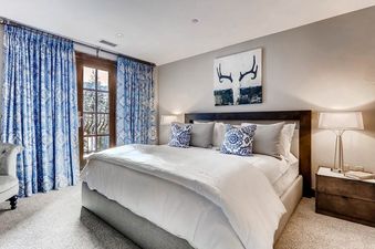 A bedroom with a king size bed, two nightstands with lamps, and a window with a view of the snowy mountains.