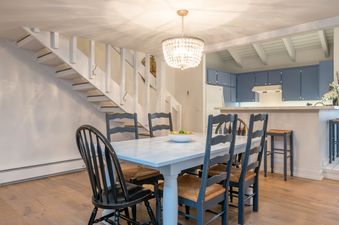 A dining room with a white table and chairs and a white ceiling.