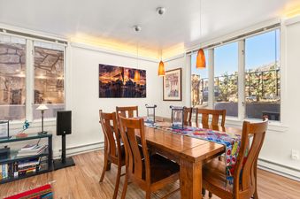 A spacious dining room in Chateau Dumont Unit 23 with a large wooden table, chairs, and bright windows.