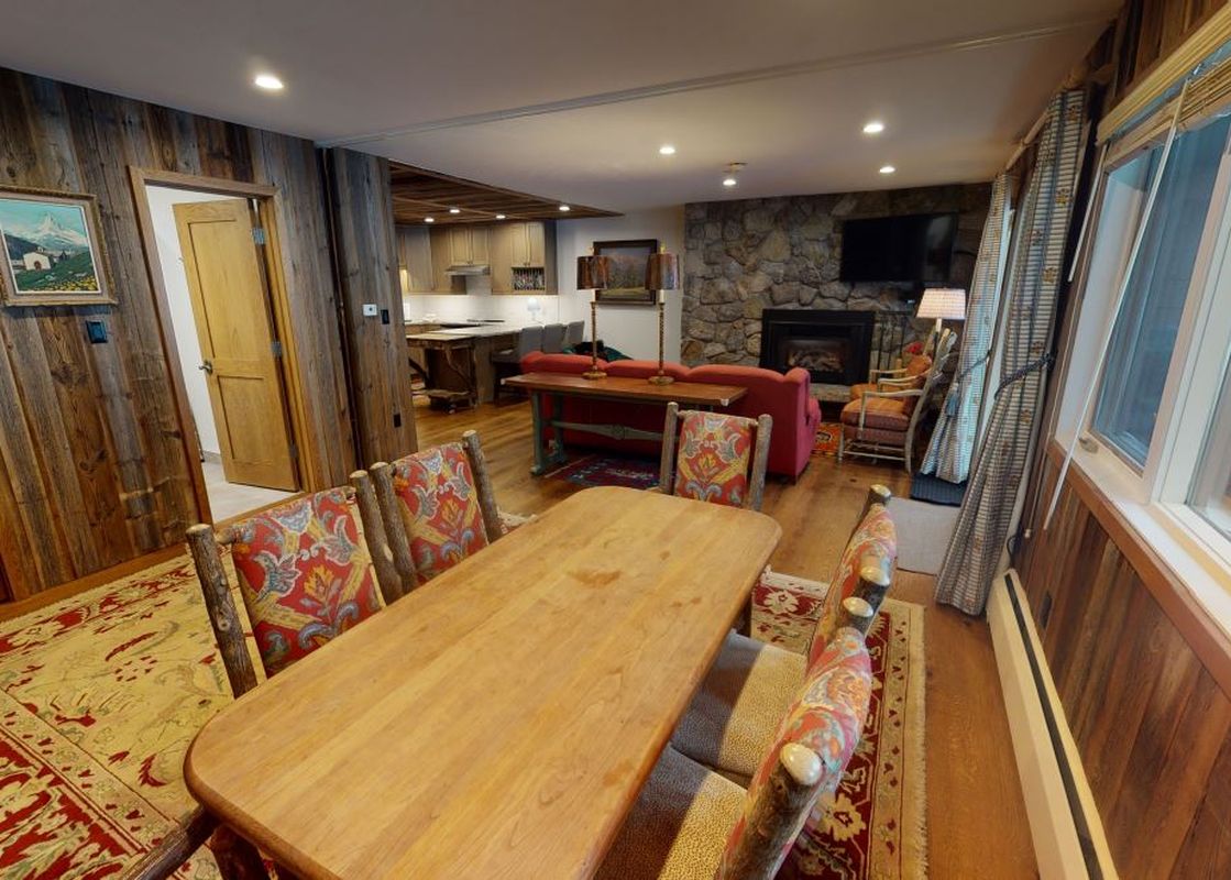 The dining room at Manor Vail 148A has a wood table with four chairs and a view of a fireplace.